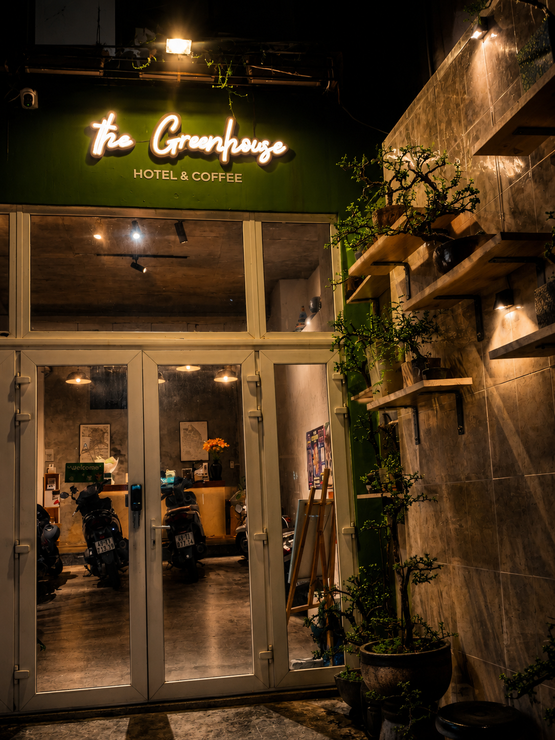 The Greenhouse Hotel & Coffee — nighttime exterior with neon sign